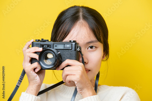 Portrait of a surprise girl with a camera in hand on a yellow background. Isolated studio. © stcom