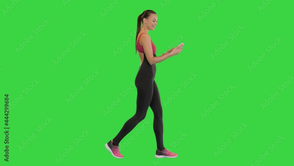 Sporty woman with smartphone walking on a Green Screen, Chroma Key. Sporty woman with smartphone walking on a Green Screen, Chroma Key.