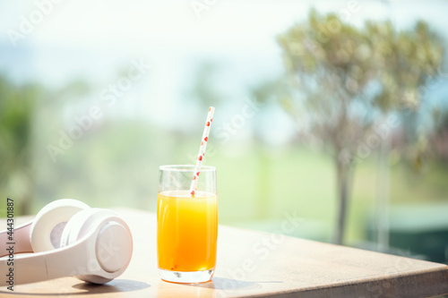 Headphones, orange juice on the table in the palm tree forest. Summer vocation. Copy space. Concept