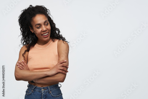 indoor shot of young african american woman smiles and looks aside into copy space. isolated over white background