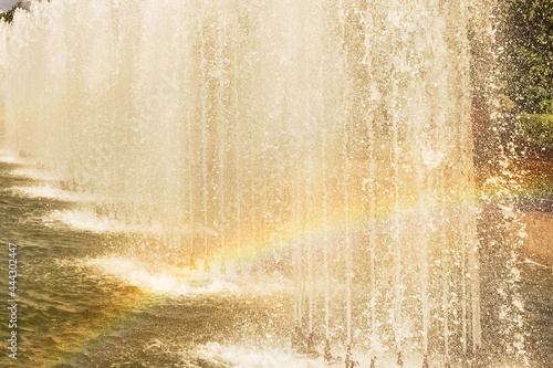 A working fountain in the park with a rainbow from splashes