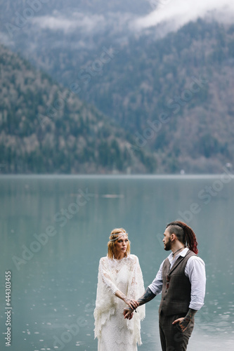 The concept of a wedding. A happy married couple in love in wedding clothes hugs stands in the middle of a boat pier a lake and misty mountains in nature in a fabulous place outdoors