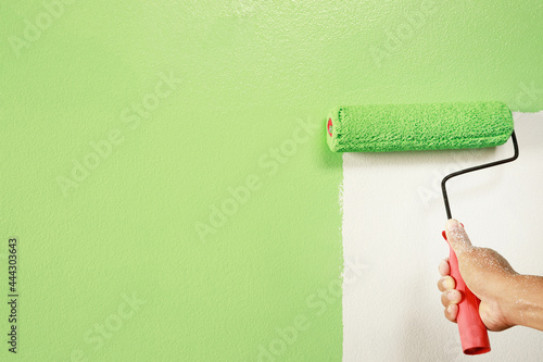 Roller Brush Painting, Worker painting on surface wall Painting apartment, renovating with green color paint. Leave empty copy space white to write descriptive text beside.