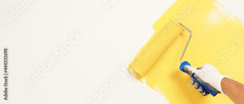 Roller Brush Painting, Worker painting on surface wall Painting apartment, renovating with yellow color paint.