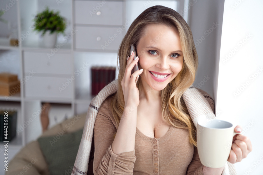 Photo of charming lady hold cup drink coffee make phone call covered plaid wear beige shirt in cozy room indoors Photo of charming lady hold cup drink coffee make phone call covered plaid wear beige shirt in cozy room indoors