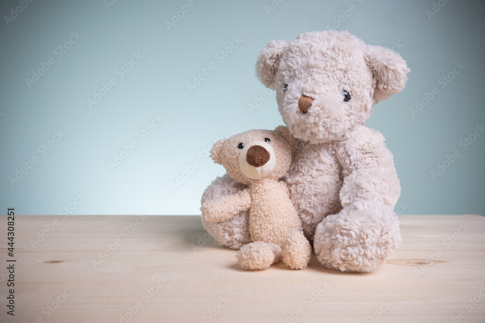 Fototapeta premium Concept family, love, and valentines festival. Big and little brown teddy bears sitting huggy show love, happiness on an old wooden table with copy space.