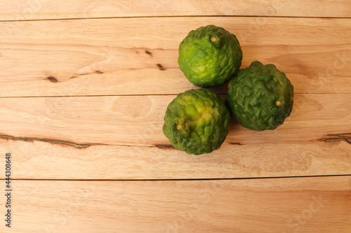 Citrus hystrix green fruits fresh isolated on wooden background closeup.