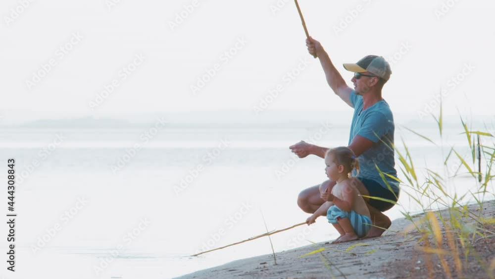 Family fishing. Father fishing with toddler daughter on the calm river with retro bamboo fishing rod Family fishing. Father fishing with toddler daughter on the calm river with retro bamboo fishing rod