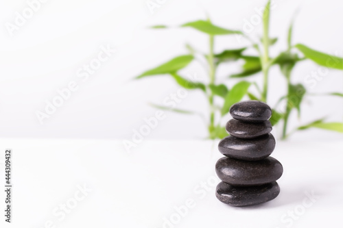 Black zen stones in a stack on white background with bamboo..