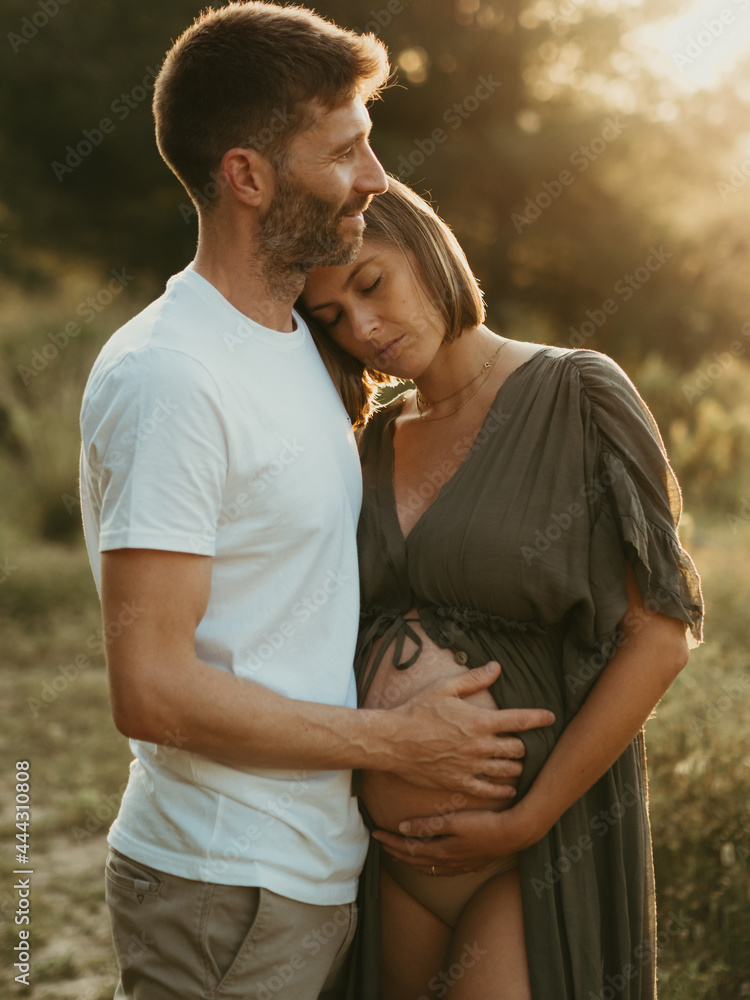 Content man embracing pregnant woman in nature Content man embracing pregnant woman in nature