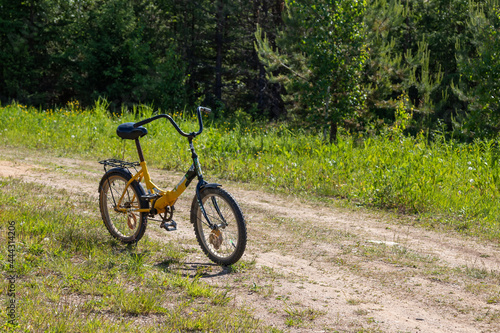 bicycle with a yellow frame stands on a country village road