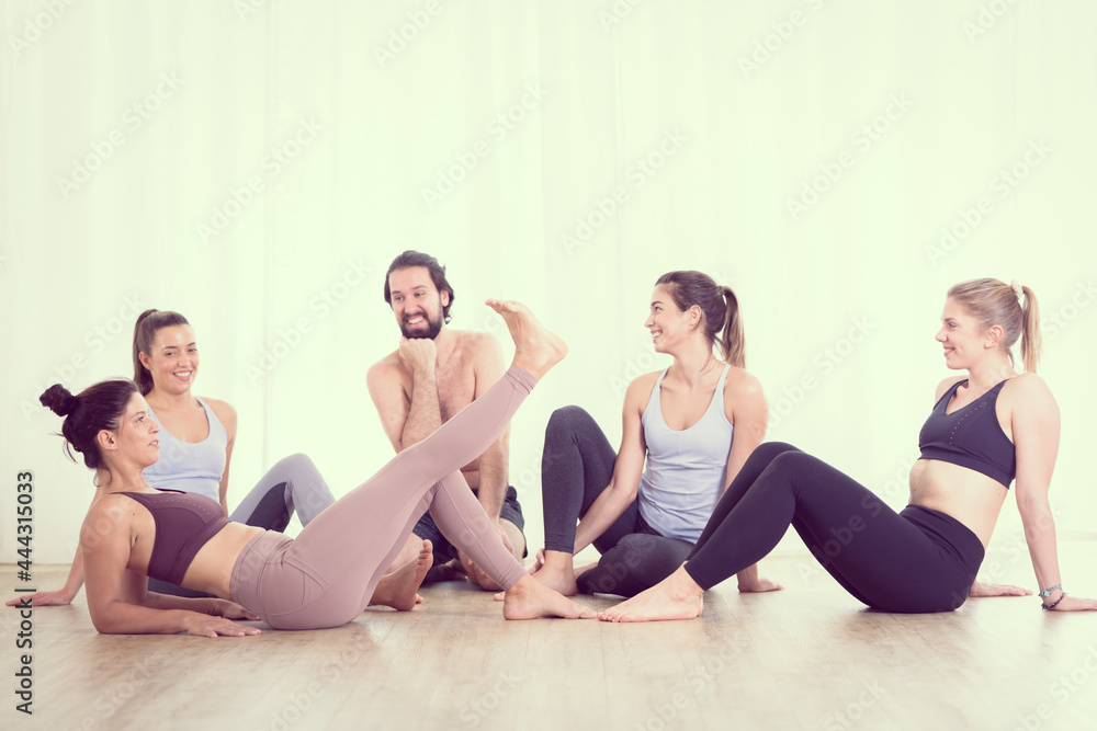 Group of young sporty attractive people in yoga studio, relaxing and socializing after hot yoga class. Healthy active lifestyle, working out in gym. Group of young sporty attractive people in yoga studio, relaxing and socializing after hot yoga class. Healthy active lifestyle, working out in gym.