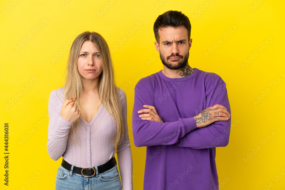 Obraz premium Young couple over isolated yellow background annoyed angry in furious gesture