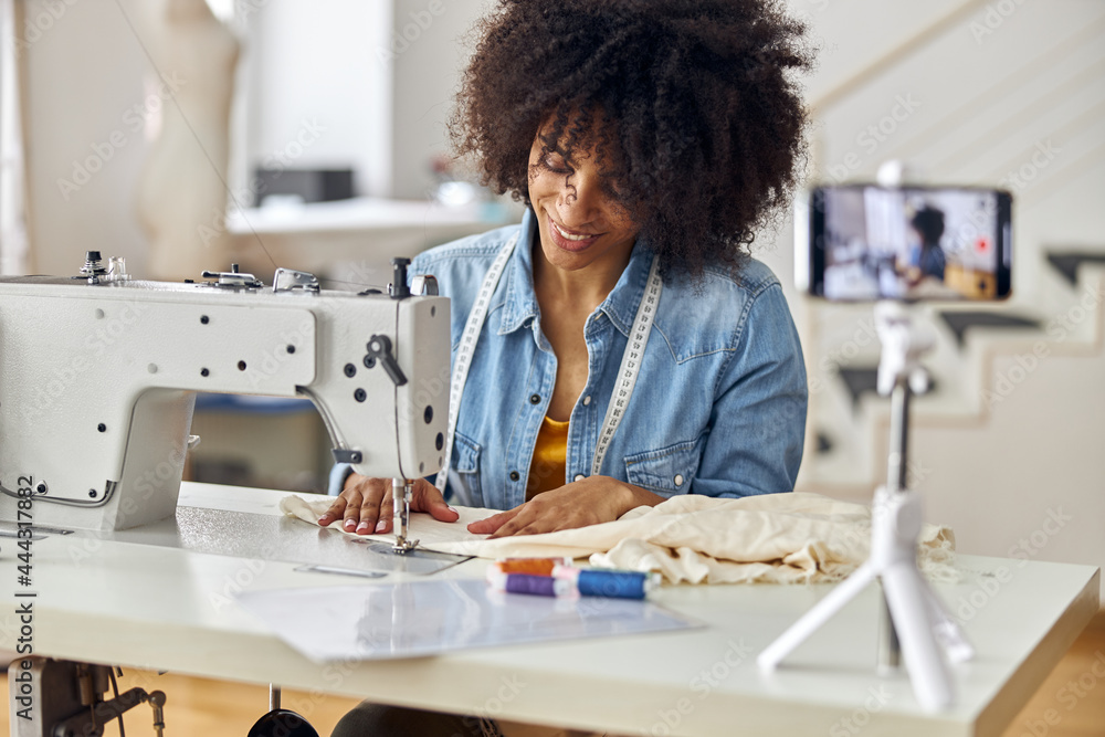 African-American seamstress sews clothes shooting video for blog in studio