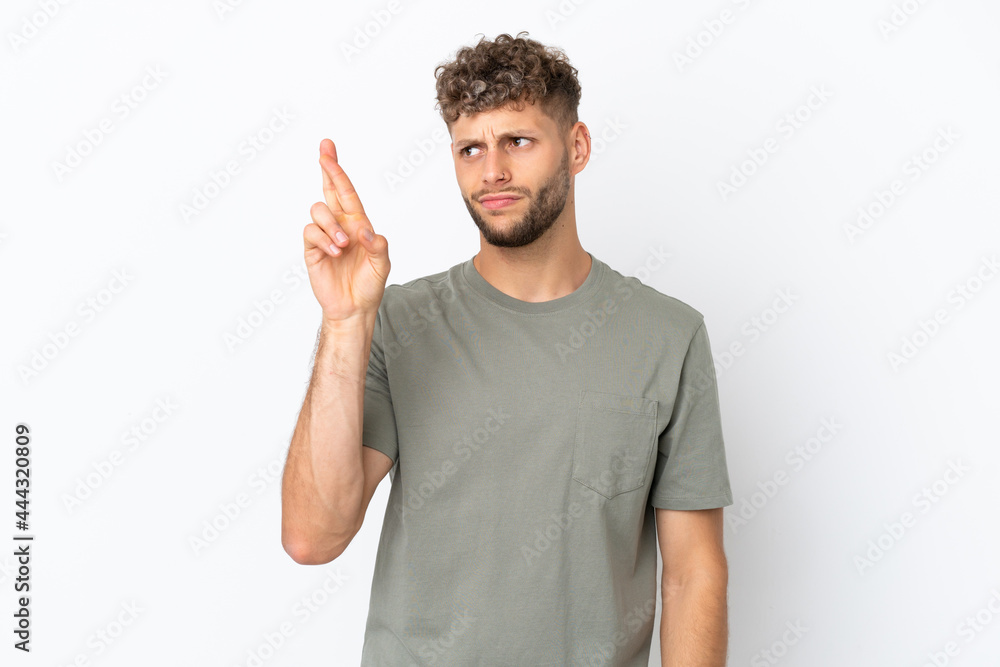 Young caucasian handsome man isolated on white background with fingers crossing and wishing the best
