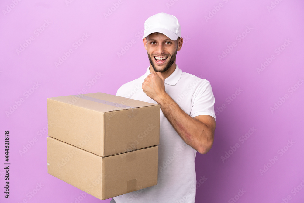 Delivery caucasian man isolated on purple background celebrating a victory Delivery caucasian man isolated on purple background celebrating a victory