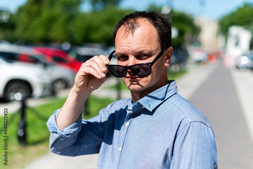Caucasian man forty years old businessman on the street takes off his sunglasses Caucasian man forty years old businessman on the street takes off his sunglasses
