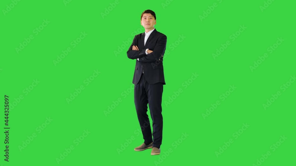 Asian man stands adjusting his suit and crossing arms on a Green Screen, Chroma Key. Asian man stands adjusting his suit and crossing arms on a Green Screen, Chroma Key.