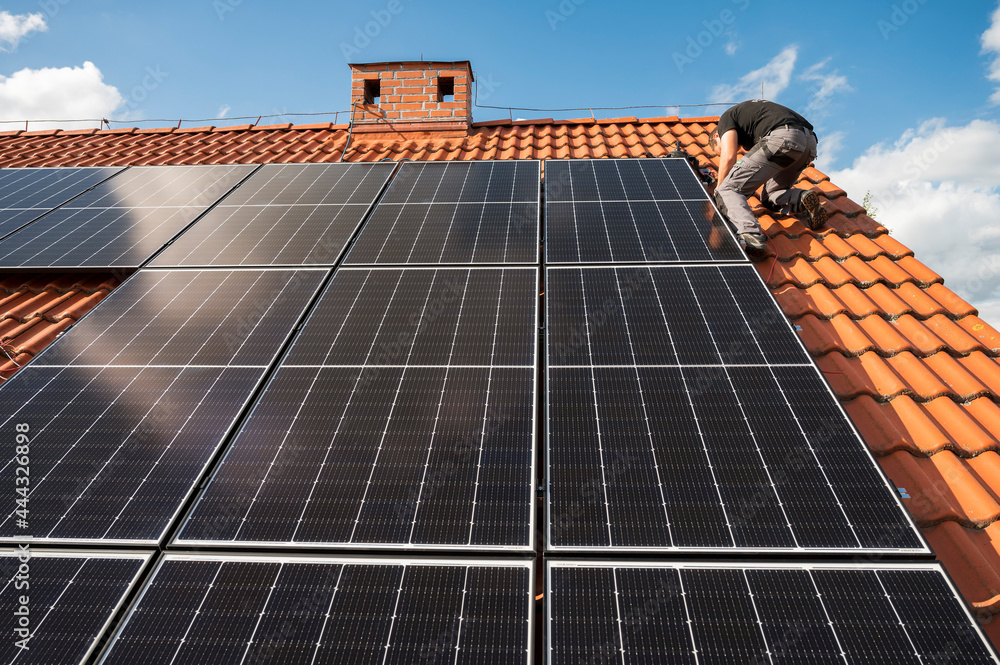 Photovoltaic panels on the roof and intaller in the background