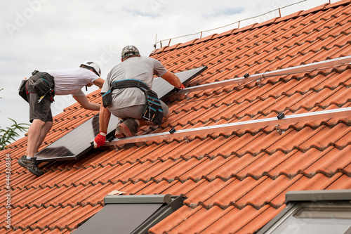 Quadro em tela Two engineers on the house roof assemble photovoltaic panel.