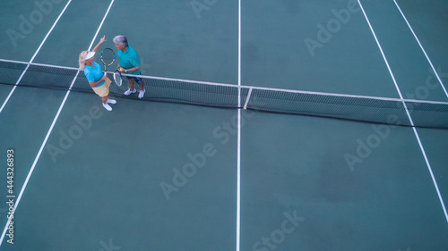 Overhead view of senior couple playing tennis on sunny day.