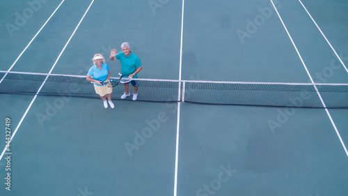 Overhead view of senior couple playing tennis on sunny day.