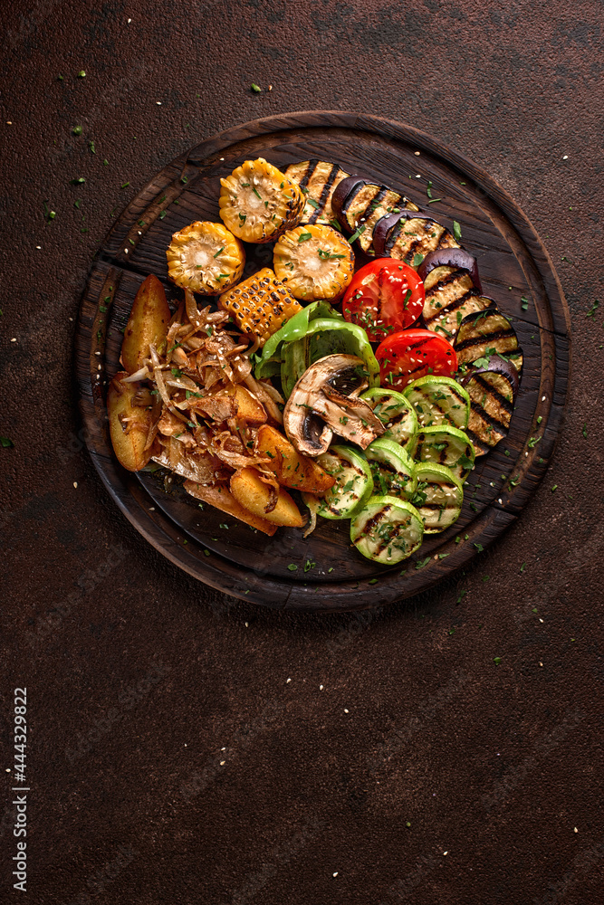 banner. a large portion of colored fried vegetables and mushrooms on a wooden tray on a dark background.