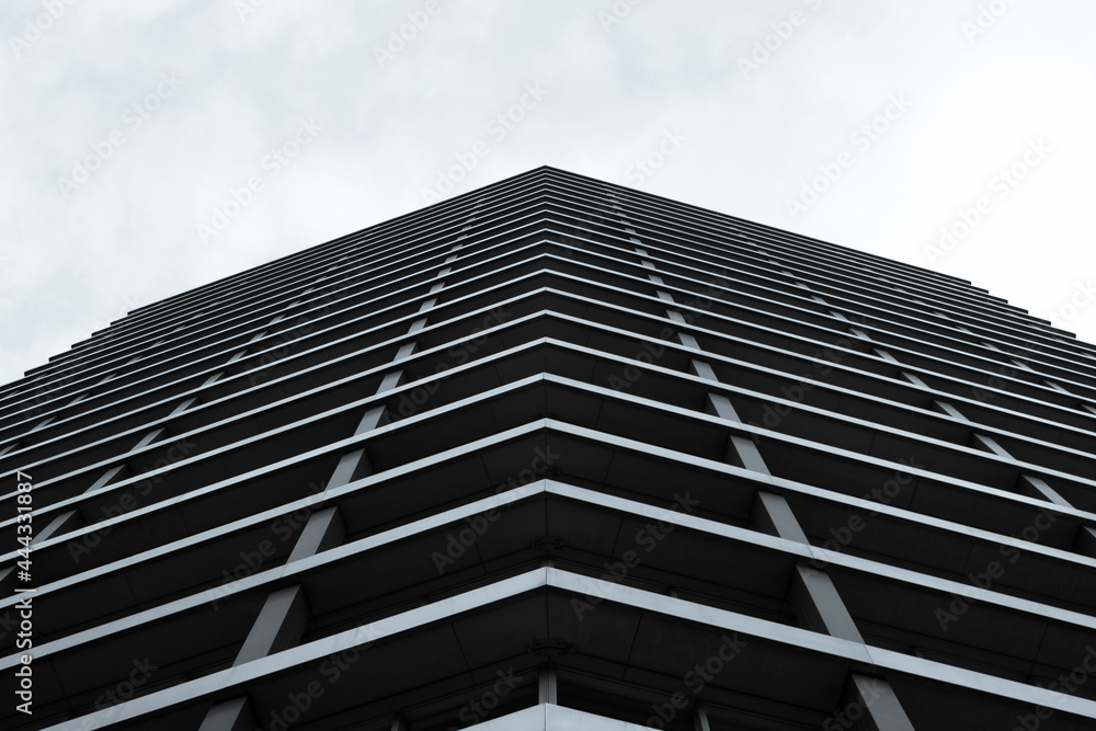 Looking up shot of a business building. The structure is metallic with a monochromatic tone pointing towards a bright white sky. Looking up shot of a business building. The structure is metallic with a monochromatic tone pointing towards a bright white sky.