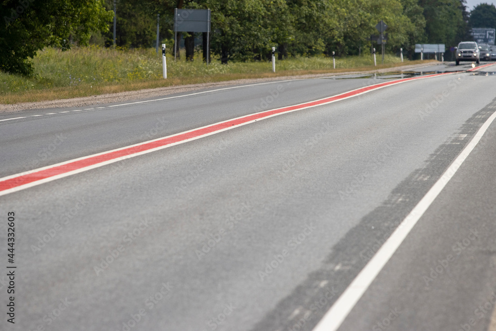 Asphalt road. Double lane road stripes  white and red. Selective focus