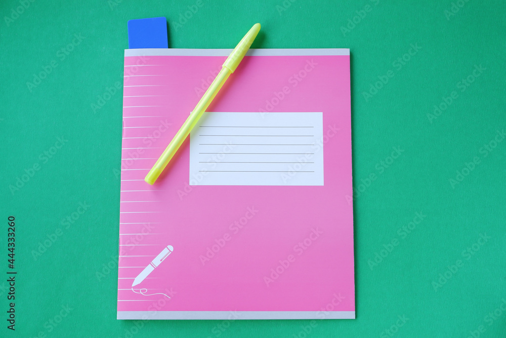 Pink notebook with stationery accessories on a green background. 1 September is the day of knowledge. Pink notebook with stationery accessories on a green background. 1 September is the day of knowledge.