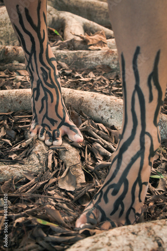 Feet with painted roots surrounded by roots in a park