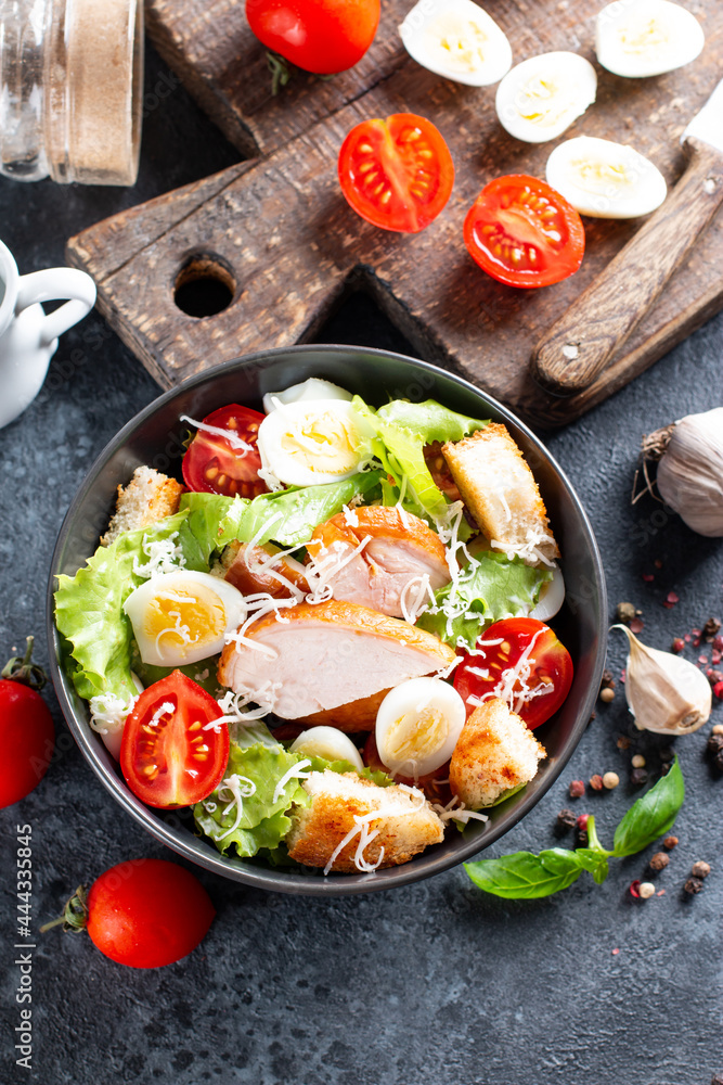 Caesar Salad with smoked chicken and parmesan on dark background. Top view Caesar Salad with smoked chicken and parmesan on dark background. Top view