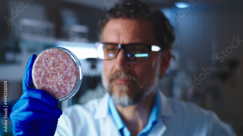 Middle aged man examining Petri dish with lab grown meat