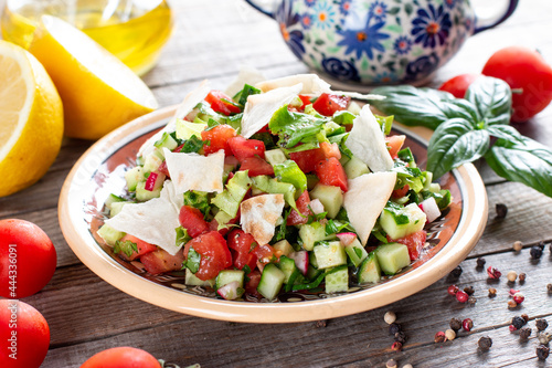 Vegetarian fattoush salad on table. Traditional Middle Eastern salad with toasted pita bread and vegetables. Lebanese cuisine. photo