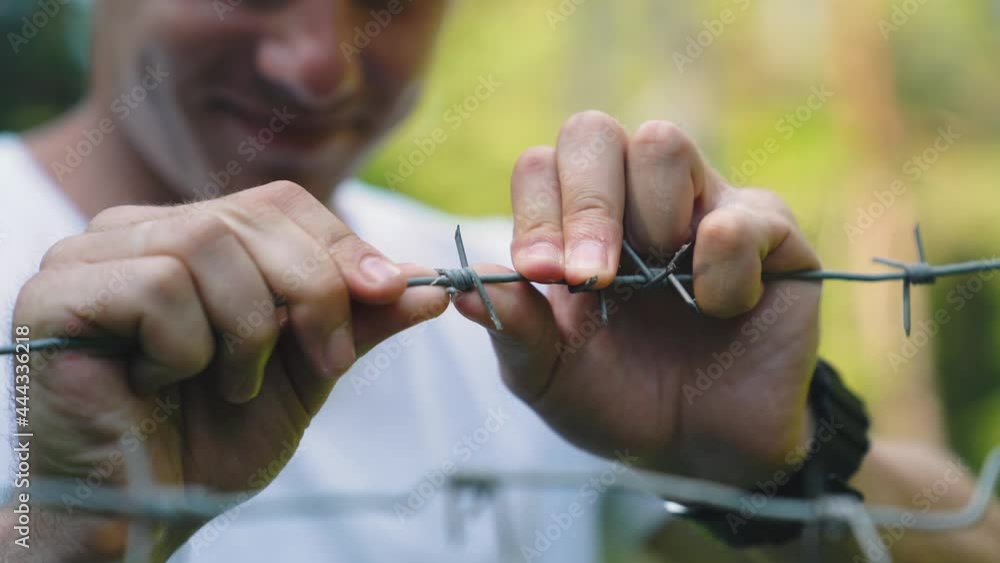 Close-up of Mans hand touching barbed wire in prison. Close-up of Mans hand touching barbed wire in prison.