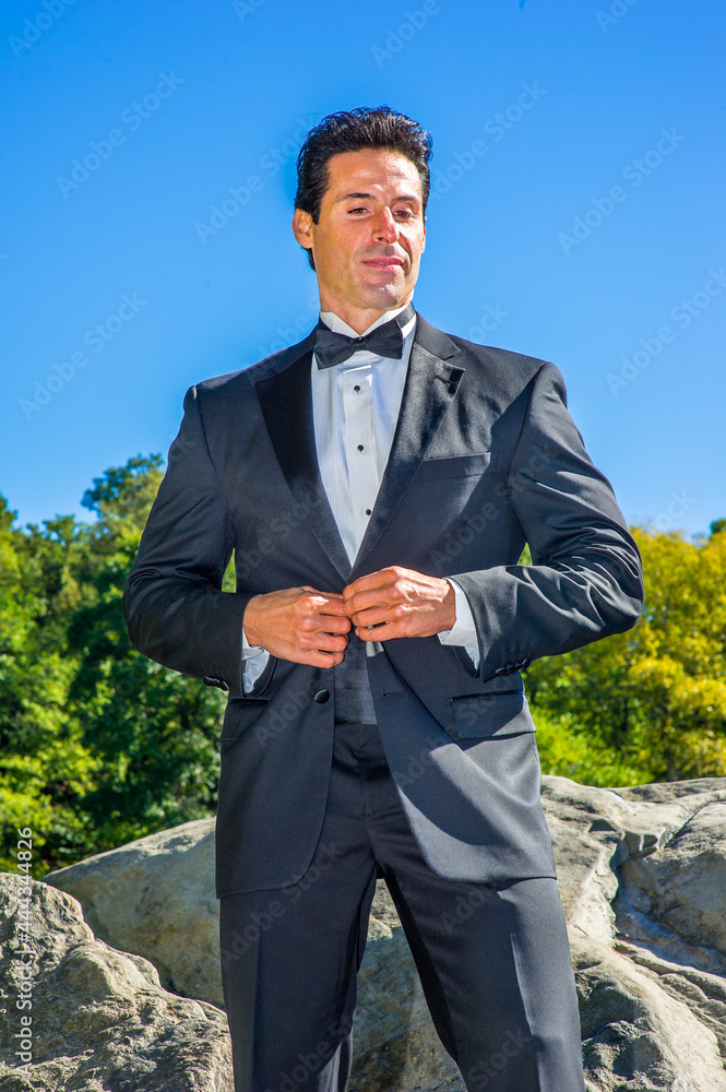 A professional executive is dressing in a black tuxedo, looking down and thinking.. A professional executive is dressing in a black tuxedo, looking down and thinking..