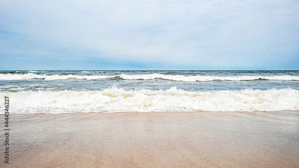 Sea waves on the beach and overcast sky