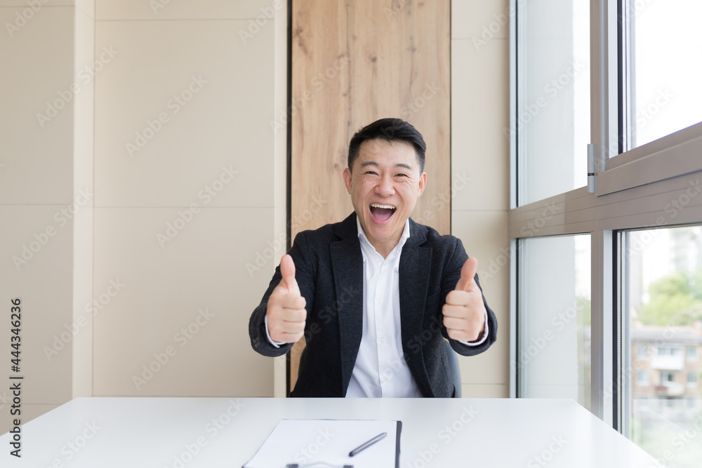 portrait of happy young asian male office worker looking at camera and smiling indoors. Close up of a friendly manager in a formal suit and white shirt sitting at work. business man feeling receiving portrait of happy young asian male office worker looking at camera and smiling indoors. Close up of a friendly manager in a formal suit and white shirt sitting at work. business man feeling receiving