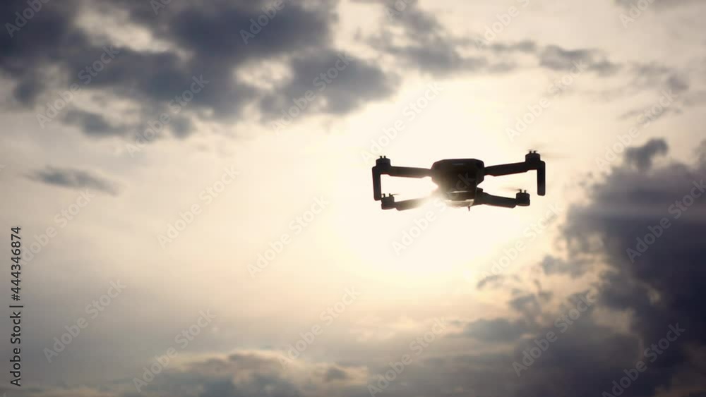 The drone is flying in the cloudy sky in a slow motion. Copter is filming in air. Its propellers are spinning. Theme of modern electronic devices. Using innovations in every day life. Clever equipment The drone is flying in the cloudy sky in a slow motion. Copter is filming in air. Its propellers are spinning. Theme of modern electronic devices. Using innovations in every day life. Clever equipment
