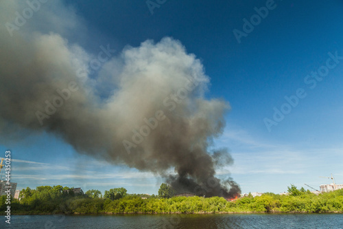 A huge column of black smoke rises from a fire near the river