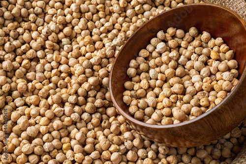 Raw chickpeas in a wooden bowl in a bag of chickpea beans. Legume dietary fibers and vegetable protein for healthy eating. Dry organic chickpeas for cooking hummus. Copy space.