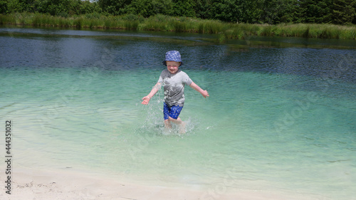 Small boy with a blue sun hat playing on a fresh water sandy beach in Vacation resort in Ireland © peter