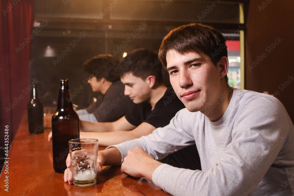 Portrait of a young man drinking beer in a bar.