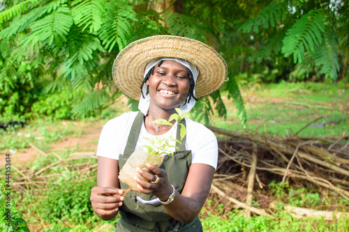 Obraz na plátne African female gardener, florist or horticulturist wearing an apron and a hat, h