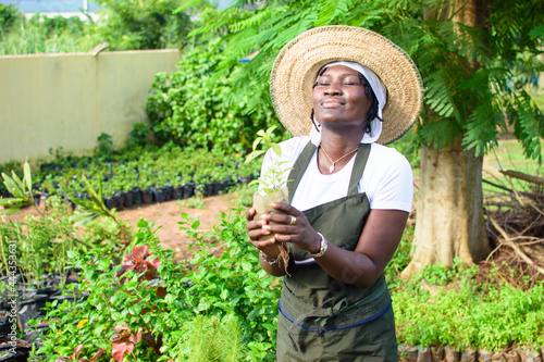 Obraz na plátně African female gardener, florist or horticulturist wearing an apron and a hat, h