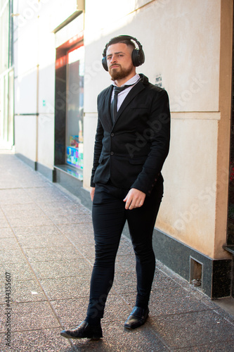 retrato de hombre caucásico con barba formal con auriculares caminando por la ciudad 
