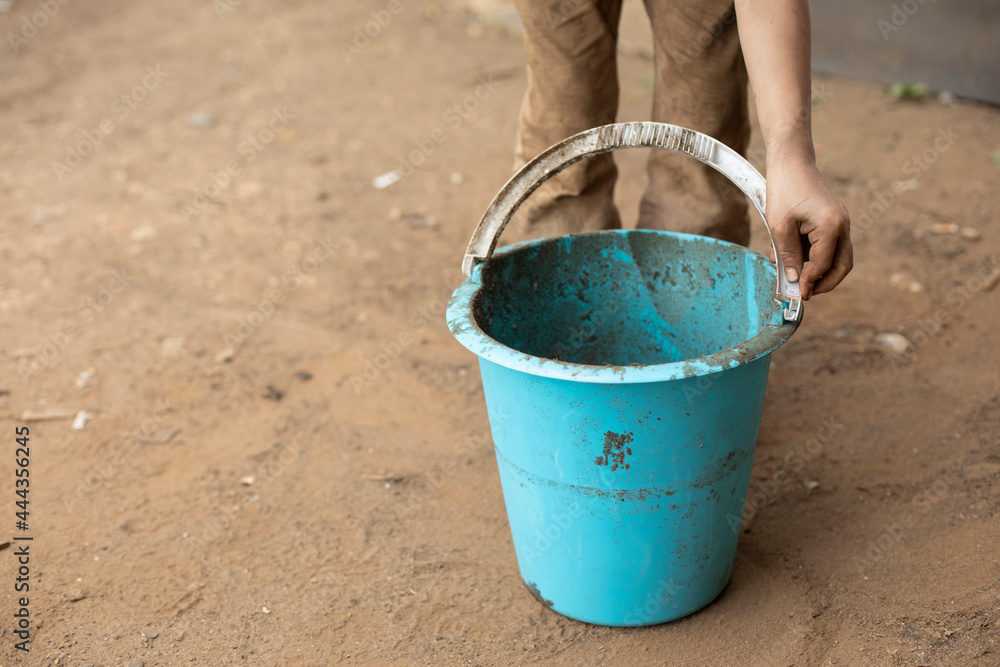 The child is holding a bucket. Blue bucket in hand. The child is holding a bucket. Blue bucket in hand.