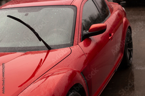 Red car in the parking lot. Car surface. Wet car after rain.