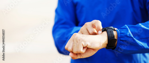 Athlete checking his wrist watch race timer running ready on practice outdoor field.