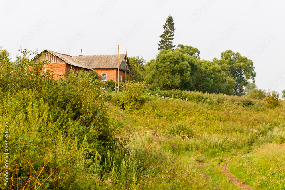 Brick house on the background of a green landscape.